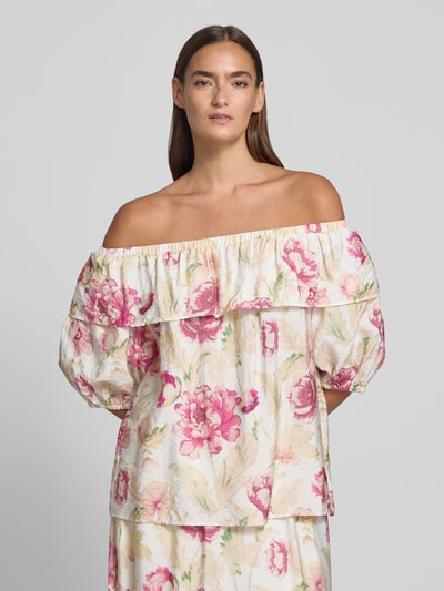Frauenmodel trägt Regular Fit Bluse aus Viskose-Mix Modell 'Maise' von FREE/QUENT mit floraler Allover-Print, Halbarm, Rüschenbesatz, helle Grundfarbe mit rosa Blüten, Rückenlänge 54 cm, Ärmellänge 27 cm, Ganzkörperansicht von vorne.