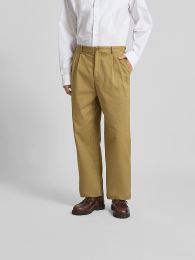 Männermodel trägt Relaxed Fit Stoffhose aus Baumwolle von MAISON KITSUNÉ in Beige mit Eingriffstaschen, Ganzkörperansicht von vorne.