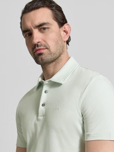 Männermodel trägt Slim Fit Poloshirt aus reiner Baumwolle Modell 'PALOSH 30' von BOSS, unifarben, Label Print, Nahaufnahme Oberkörper.