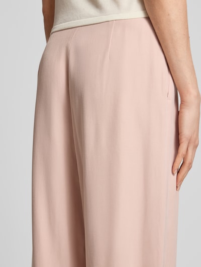 Frauenmodel trägt Bundfaltenhose aus Viskose-Mix mit Knopfverschluss von Jake*s Collection in zartem Rosa, glatte Textur, Detailaufnahme Rückansicht, Damen Hose, Wide Leg, Bundfalten, Bundweite 37 cm, Innenbeinlänge 80 cm bei Größe 36.