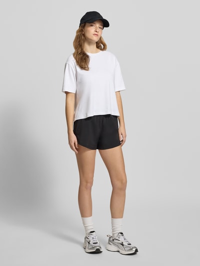 Frauenmodel trägt Regular Fit Shorts mit elastischem Bund von PUMA, Schwarz, Logo-Print, weit geschnitten, Ganzkörperansicht von vorne.