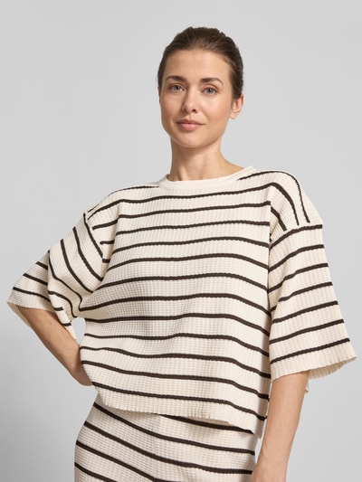 Frauenmodel trägt Oversized T-Shirt aus Viskose-Mix Modell 'NURIA' von VILLA SOPHIE, Optik: Allover-Muster, Rippstrick, Label-Applikation, Rundhals, Kurzarm, creme mit braunen Streifen, Material: Viskose-Mix. Nahaufnahme Oberkörper.
