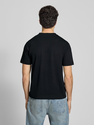 Männermodel trägt T-Shirt mit Label-Stitchings Modell 'VENIRE' von Ellesse, Schwarztöne, Reine Baumwolle, Regular-Fit, Ganzkörperansicht Rückansicht.