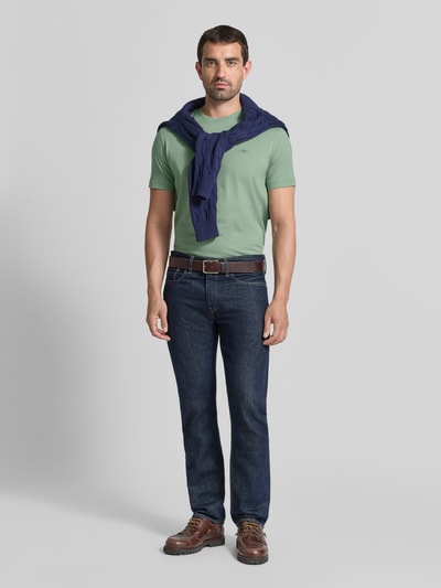 Mannelijk model draagt Regular Fit t-shirt uit puur katoen van GANT Heren in lichtgroen, donkere jeans, Ganzkörperansicht van voren.