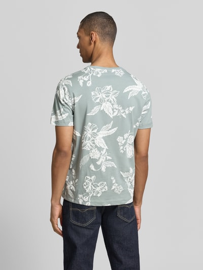 Męskimodel nosi T-Shirt mit Rundhalsausschnitt und Label-Detail von Lerros z bawełny, prosty krój, okrągły dekolt, detal z logo, długość tyłu w rozmiarze M: 70 cm, wzór kwiatowy na jasnozielonym tle, widok całej sylwetki z tyłu