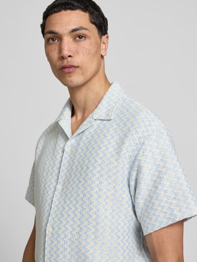Męski model nosi Regular Fit Freizeithemd im Allover-Look Modell 'MONTAUK' od Jack & Jones; mieszanka materiałów, niebiesko-żółty wzór; krój regular fit, kołnierz rewersowy, krótki rękaw; długość tyłu w rozmiarze M: 71 cm, szerokość w rozmiarze M: 50 cm, długość rękawa w rozmiarze M: 22 cm; zbliżenie na górną część ciała.