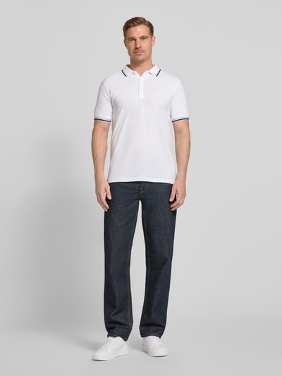 Männermodel trägt Relaxed Fit Poloshirt mit Kontraststreifen von Lindbergh aus Reiner Baumwolle, Knopfleiste, Label-Stitching, Ganzkörperansicht von vorne. Rückenlänge bei Größe M: 67 cm.