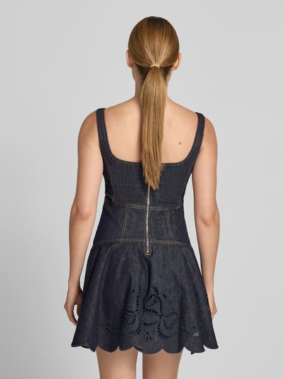 Frauenmodel trägt Minikleid in Denim-Optik von Self-Portrait, Dunkelblau, Baumwoll-Mix, Loch-Stickereien, Ärmelloses-Design, taillierte Passform, Ganzkörperansicht Rückansicht.