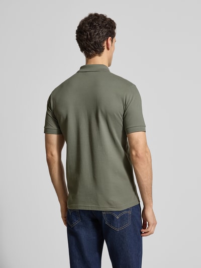 Männermodel trägt Slim Fit Poloshirt aus Baumwoll-Mix Modell 'PASSENGER' von BOSS Orange in Olivgrün, Piqué-Textur, unifarben, Ganzkörperansicht Rückansicht.