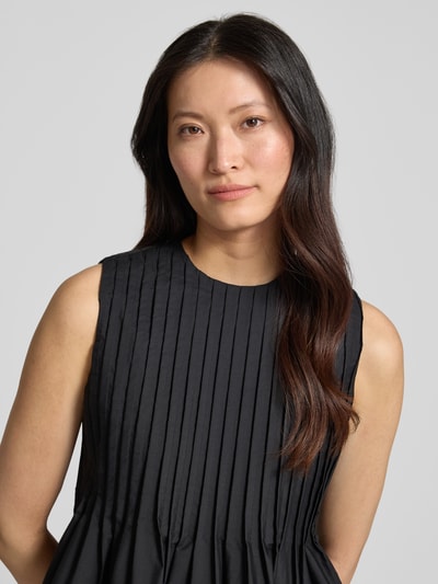 Frauenmodel trägt Bluse mit gelegten Falten von Copenhagen Muse, Material-Mix mit Baumwoll-Anteil, Ärmelloses-Design, Nahaufnahme Oberkörper.
