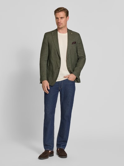 Männermodel trägt Sakko aus viscose met pochet model 'Tebbo' van Carl Gross, regular fit, olijfgroen, geheel van voren, context: heren colbert van Carl Gross, zuiver viscose, regular fit, model 'Tebbo', reverskraag, labeldetail, knoopsluiting, paspelzak op de borst met pochet, zij-steekzakken, ruglengte bij maat 50: 75 cm, schouderbreedte 48 cm, mouwlengte 65 cm, geheel van voren.