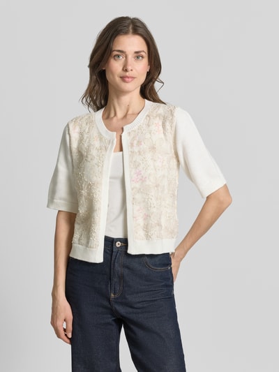 Frauenmodel trägt Regular Fit Cardigan mit floralem Design von More & More, helles Baumwoll-Mix, Ziersteinbesatz, Halbarm, Ganzkörperansicht von vorne.