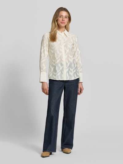 Frauenmodel trägt Bluse aus Viskose-Mix mit Strukturmuster Modell 'CRUZ' von Mango, Damen, Regular-Fit, Hemdblusenkragen, Knopfleiste, Rückenlänge 62 cm, Ärmellänge 60 cm, cremefarben, florale Struktur, transparente Optik, Ganzkörperansicht von vorne.