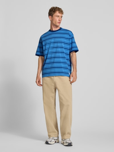Männermodel trägt Regular Fit T-Shirt aus reiner Baumwolle Modell 'Nistripe' von HUGO Blue mit blauen Streifen, Ganzkörperansicht von vorne.