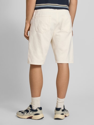 Männermodel trägt Baggy Fit Jeansshorts Modell 'ALEX' von Jack & Jones in Offwhite mit Eingrifftaschen aus reiner Baumwolle, Ganzkörperansicht Rückansicht.