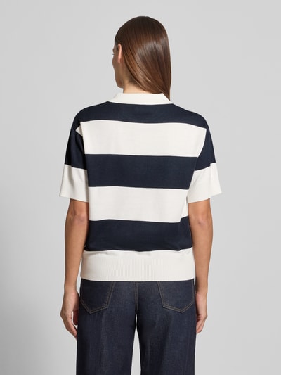 Frauenmodel trägt Regular Fit Poloshirt aus Viskose-Mix Modell 'LULS' von ICHI, breite Streifen in Dunkelblau und Weiß, Strick-Optik, Ganzkörperansicht Rückansicht.