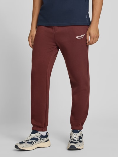 Männermodel trägt Straight Fit Sweatpants aus Baumwoll-Mix Modell 'Kane' von JACK & JONES, elastische Bündchen, Logo-Detail, Ganzkörperansicht von vorne.