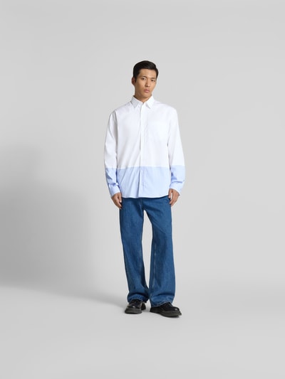 Männermodel trägt Regular Fit Freizeithemd aus Baumwolle von VETEMENTS, weiß-blau, Durchgehende Knopfleiste, Brusttasche, Langärmelig, Ganzkörperansicht von vorne. Rückenlänge in Größe M 83 cm, Schulterbreite 54 cm, Ärmellänge 68 cm.