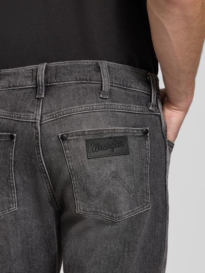 Männermodel trägt Tapered Fit Jeans aus Baumwoll-Mix Modell 'Redford' von Wrangler in Grau mit sichtbaren Nähten, Nahaufnahme Rückansicht, Herren Tapered Fit Jeans von Wrangler