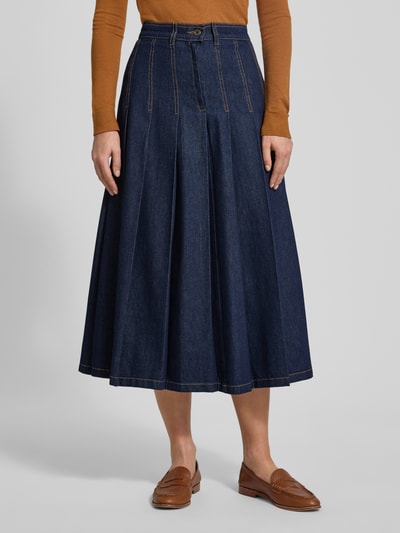 Kobiece model prezentuje rozkloszowaną spódnicę jeansową z bawełny Ausgestellter Jeansrock aus reiner Baumwolle Modell 'OVALE' od Weekend Max Mara, średni odcień niebieskiego, kontrastowe szwy, łaty z logo, długość midi, widok całej sylwetki z przodu.
