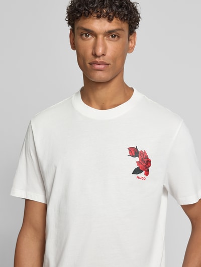 Männermodel trägt Regular Fit T-Shirt aus reiner Baumwolle Modell 'DIKERD' von HUGO, Optik: Unifarben, Motiv-Print, Label-Schriftzug, Rundhals, Kurzarm, Materialverarbeitung: Jersey, Nahaufnahme Oberkörper.