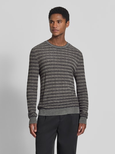 Männermodel trägt Strickpullover mit Lanawolle von Emporio Armani, grau-schwarz meliert, gerader Schnitt, Rundhalsausschnitt, Ganzkörperansicht von vorne.