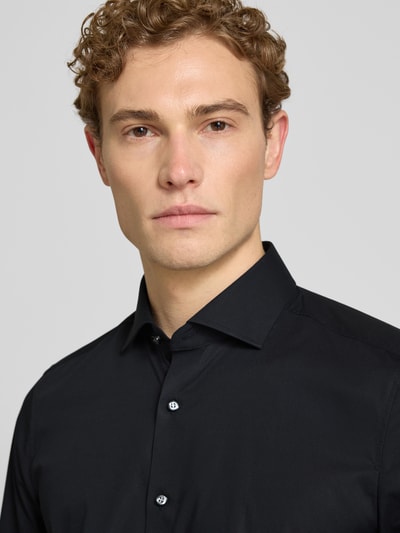 Männermodel trägt Body Fit Business-Hemd aus Baumwolle mit Kentkragen von OLYMP Level Five in Schwarz, Nahaufnahme Oberkörper.