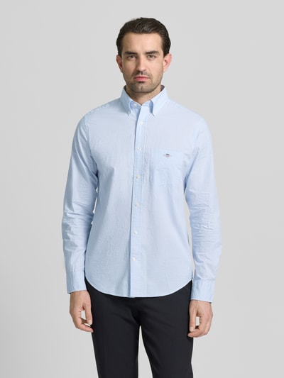 Männermodel trägt Slim Fit Freizeithemd mit Logo-Stitching von Gant in Hellblau, reine Baumwolle, Button-Down-Kragen, Langarm, Ganzkörperansicht von vorne.