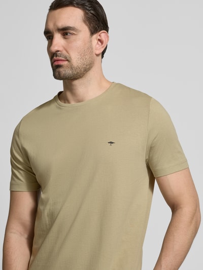 Męski model nosi T-Shirt mit Rundhalsausschnitt und Label-Stitching od Fynch-Hatton, bawełna, krój regular fit, okrągły dekolt, wyhaftowane logo, długość tyłu w rozmiarze M: 71 cm, jasnobeżowy kolor, gładka struktura, półzbliżenie przód