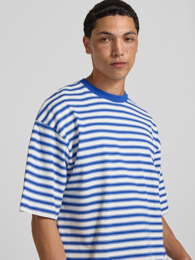 Männermodel trägt Oversized T-Shirt mit Label-Stitching von REVIEW, blau-weiß gestreift, Reine Baumwolle, Allover-Look, Rundhalsausschnitt, Nahaufnahme Oberkörper.