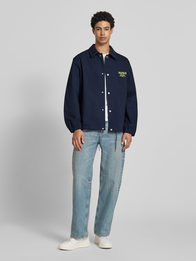 Männermodel trägt Regular Fit Hemdjacke aus reiner Baumwolle Modell 'BIYO' von HUGO, dunkelblauer Twill, Optik: Unifarben, Ganzkörperansicht von vorne.