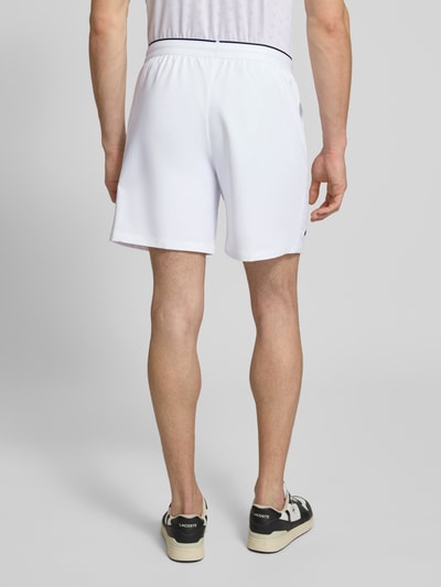 Männermodel trägt weiße Regular Fit Sport-Shorts mit elastischem Bund von Lacoste Sport, unifarben, Logo-Patch, Rückansicht Ganzkörperansicht.