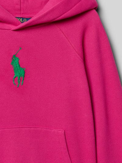 Mädchen trägt Regular Fit Hoodie aus Baumwoll-Mix von Polo Ralph Lauren Teens in Pink mit grünem Logo-Stitching, Sweat-Textur, Nahaufnahme Oberkörper.