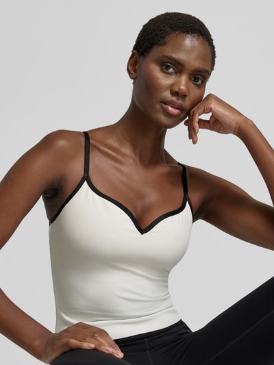 Frauenmodel trägt Trägertop mit Spaghettiträgern Modell 'Sense' von aim'n, V-Ausschnitt, cremefarbener Material-Mix mit Stretch, Nahaufnahme Oberkörper.