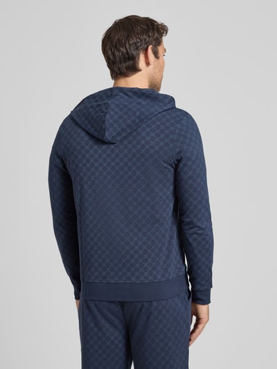 Männermodel trägt Sweatjacke mit Logo-Muster und Kapuze von JOOP! Collection aus Reiner Baumwolle, Regular-Fit, Rückenlänge 69 cm, Ganzkörperansicht Rückansicht.