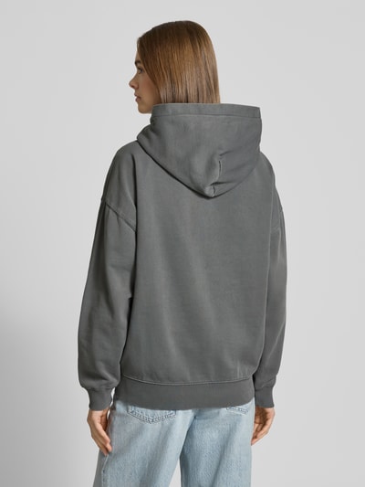 Vrouwenmodel draagt Oversized Hoodie met logo en kangoeroezak model 'CLARITA' van Pegador in katoenmix, grijs, Ganzkörperansicht Rückansicht.