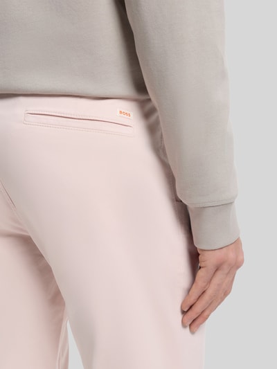Männermodel trägt Slim Fit Chino aus Baumwoll-Mix von BOSS Orange, Optik: Unifarben, Twill-Struktur, Nahaufnahme Gesäßtasche, Rückansicht.
