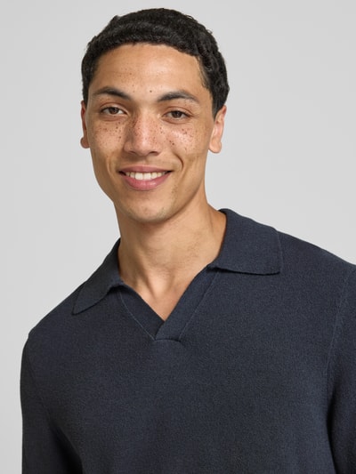 Męski model nosi Regular Fit Poloshirt aus Baumwoll-Mix von Marc O'Polo Denim, ciemnogranatowy kolor, tekstura dzianiny, zbliżenie górnej części ciała.