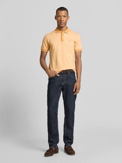 Männermodel trägt Regular Fit Poloshirt mit Logo-Stitching von Lerros in Pfirsich, Polokragen, Knopfleiste, Ganzkörperansicht von vorne.