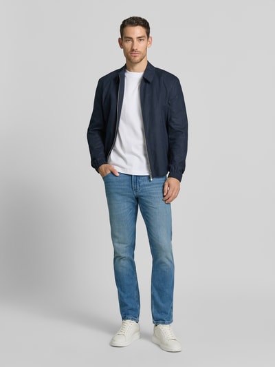 Mannelijk model draagt Jeans im Used-Look Modell 'Greensboro' van Wrangler, blauwe slim fit denim met steekzakken, katoen-elastaan mix, herenjeans, volledige lichaamsvooraanzicht.