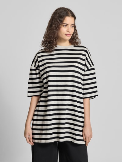 Frauenmodel trägt Oversized T-Shirt mit Label-Print von Karo Kauer aus reiner Baumwolle, Schwarz-Weiß-Streifenmuster, Rundhalsausschnitt, Ganzkörperansicht von vorne.