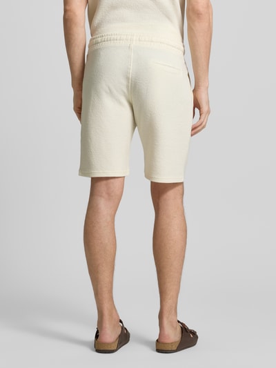 Männermodel trägt Sweatshorts mit elastischem Bund von MCNEAL, Strukturmuster, gerade Passform, Eingriff- und Gesäßtaschen, Ganzkörperansicht Rückansicht.