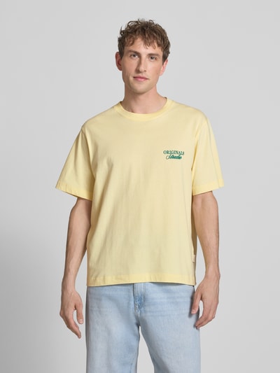 Männermodel trägt T-Shirt mit Label-Print von Jack & Jones aus reiner Baumwolle in Gelb, Relaxed Fit, Rundhalsausschnitt, Ganzkörperansicht von vorne.