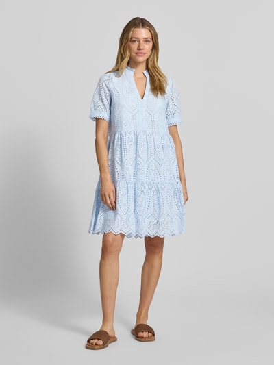 Vrouwenmodel draagt Minikleid mit Lochstickerei Modell 'Holi' van YAS, puur katoen, A-lijn, V-hals, lichtblauw, ajourwerk, ganzlichaamsvooraanzicht.