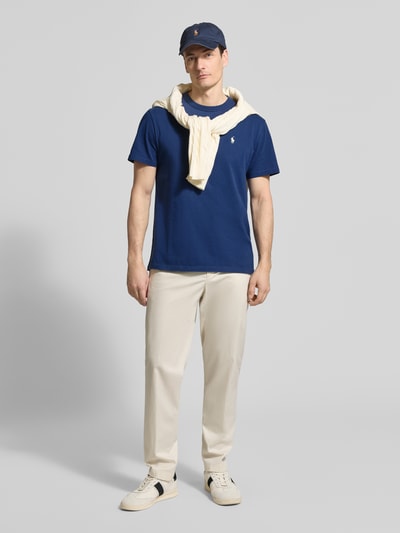 Mężczyzna nosi Regular Fit T-Shirt aus reiner Baumwolle von Polo Ralph Lauren, granatowy kolor, logo z przodu, krój regular fit, unifarbene optyka, okrągły dekolt, krótki rękaw, proste wykończenie, materiał bawełniany, widok całej sylwetki z przodu.
