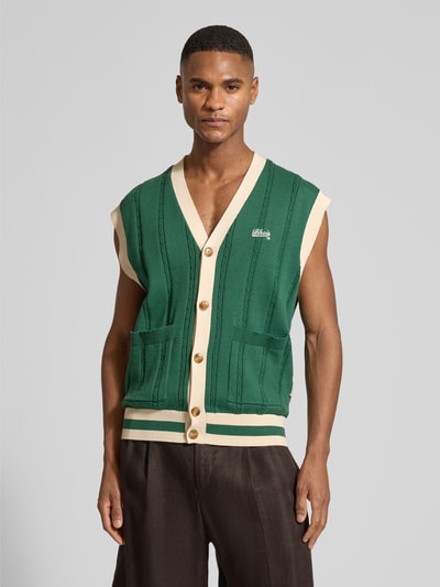 Mannelijk model draagt Regular Fit Weste in breilook met logo-stitching van BLKVIS, groen met beige, opgestikte zakken, V-hals, doorlopende knoopsluiting, vooraanzicht bovenlichaam.
