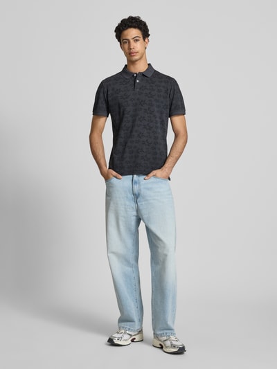 Männermodel trägt Slim Fit Poloshirt mit kurzer Knopfleiste Modell 'FRISCO' von Blend aus reiner Baumwolle, Ganzkörperansicht von vorne.