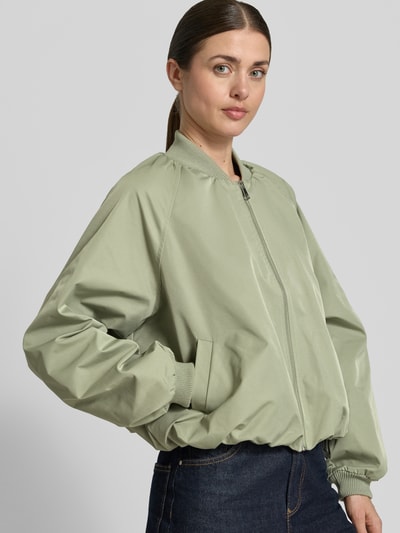Frauenmodel trägt Blouson mit elastischen Ärmelabschlüssen und Reißverschluss von Zero in hellem Grün, Loose-Fit, Ganzkörperansicht von vorne, Kurzer Stehkragen, Raglanärmel, Rückenlänge 52 cm, Schulterbreite 40 cm, Brustweite 50 cm, Ärmellänge 55 cm.