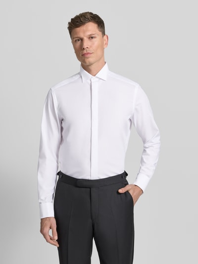 Männermodel trägt Modern Fit Business-Hemd mit verdeckter Knopfleiste von OLYMP aus reiner Baumwolle, Kentkragen, weiße glatte Textur, Ganzkörperansicht von vorne.