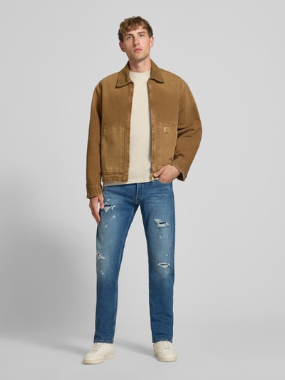 Männermodel trägt Straight Fit Jeans im Destroyed-Look Modell 'Grover' von Replay, blauer Baumwoll-Mix mit Stretch-Anteil, Ganzkörperansicht von vorne.